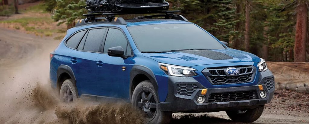 A blue new Subaru Outback traverses through a dirt road with ease, making this SUV a perfect on or off-road travel companion. Shop for your new Subaru at Subaru of Spartanburg today.