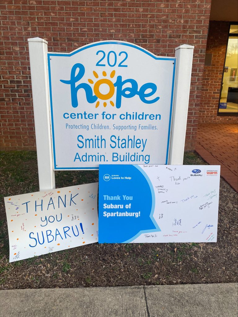 A sign showcasing the Hope Center for Children logo and thanks Subaru of Spartanburg for their participation in the Operation Warm coat drive for needy children in the Spartanburg area.