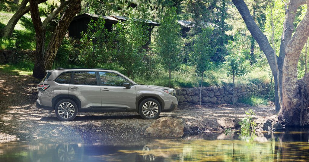 The new Subaru Forester sits parked next to a small pond.
