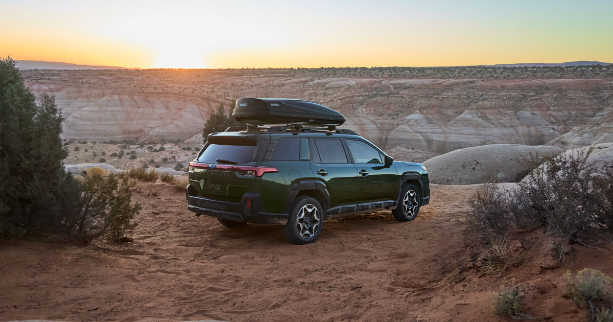 A Subaru Outback with camping accessories on top parked off-road.